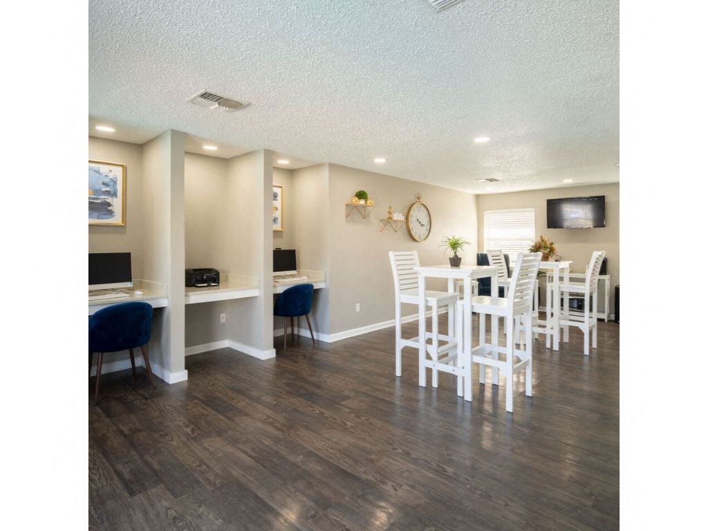 a common area with a table and chairs and a computer desk