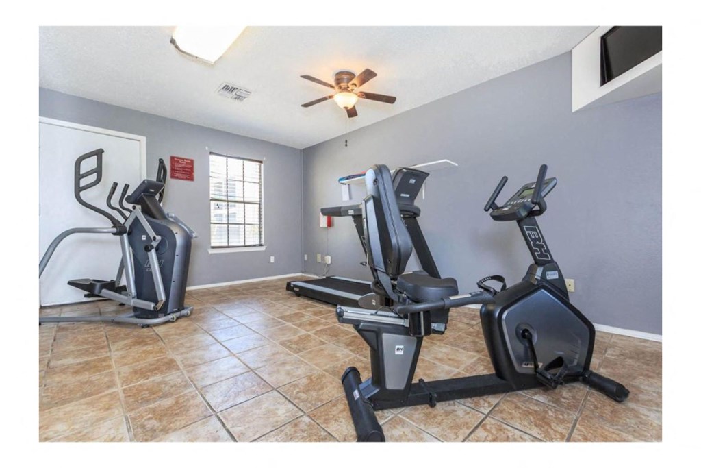 a home gym with two treadmills and a ceiling fan