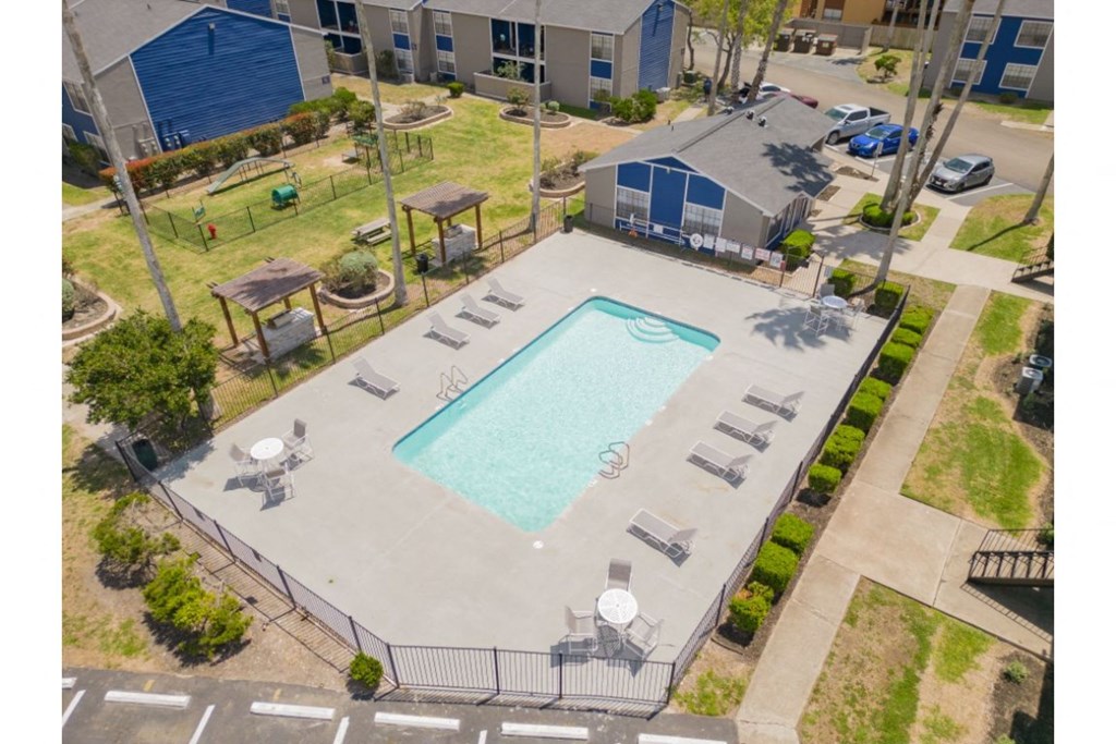a large swimming pool with lounge chairs and umbrellas in front of a building