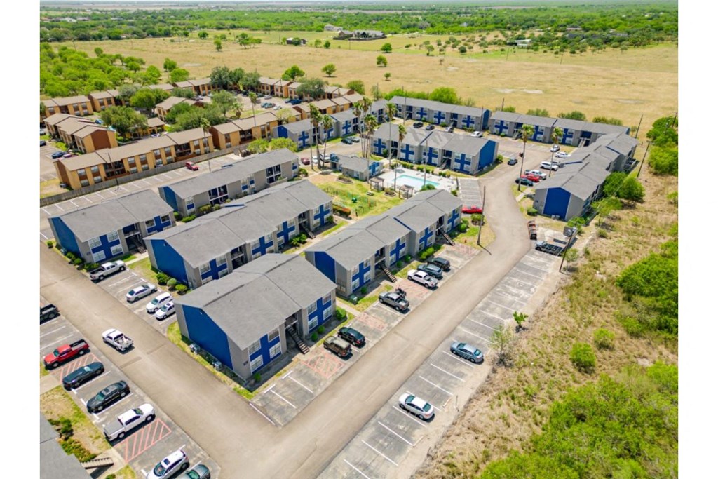 an aerial view of a group of buildings with cars parked in front of them
