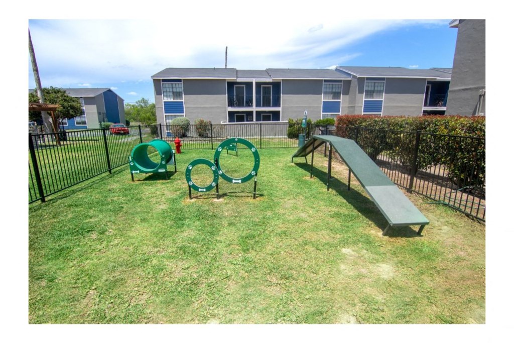 a playground with a slide and chairs in a yard with a building in the background