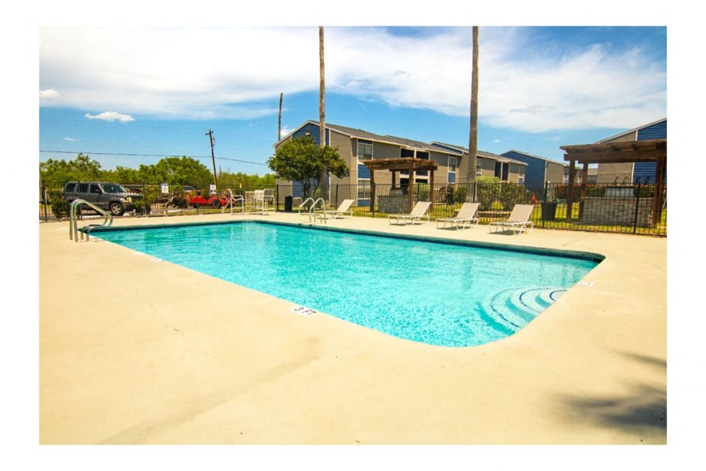 a resort style pool with chaise lounge chairs and a building in the background