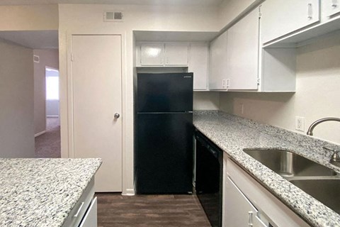 a kitchen with white cabinets and a black refrigerator