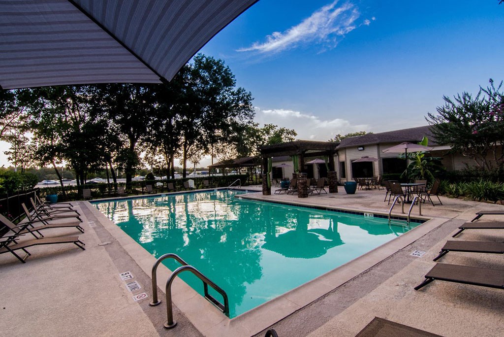 a large swimming pool with lounge chairs and umbrellas