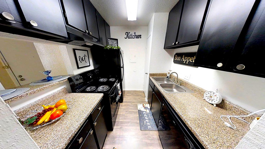 a kitchen with black cabinets and a bowl of fruit on the counter