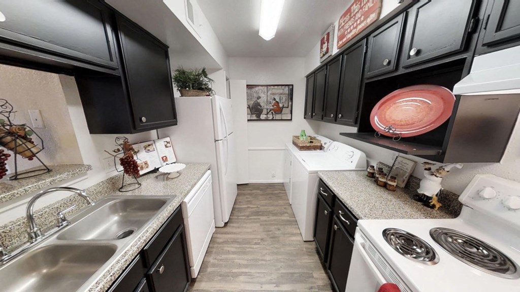 a spacious kitchen with white appliances and black cabinets