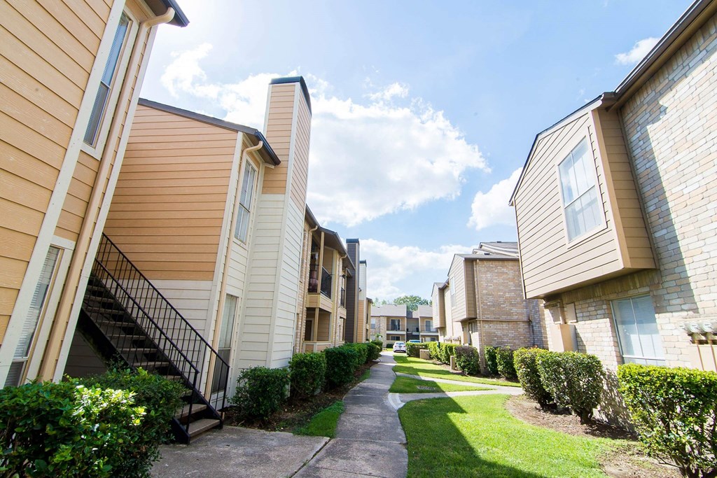 walkway between the buildings at the whispering winds apartments in pearland, tx