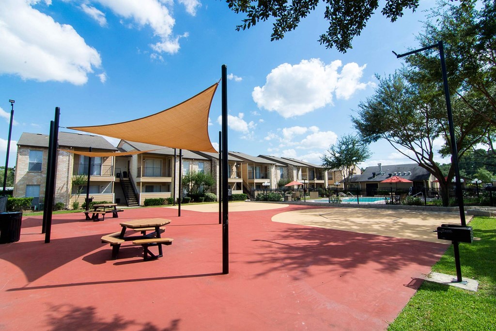 a picnic area with a picnic table and benches in front of a row of apartment buildings