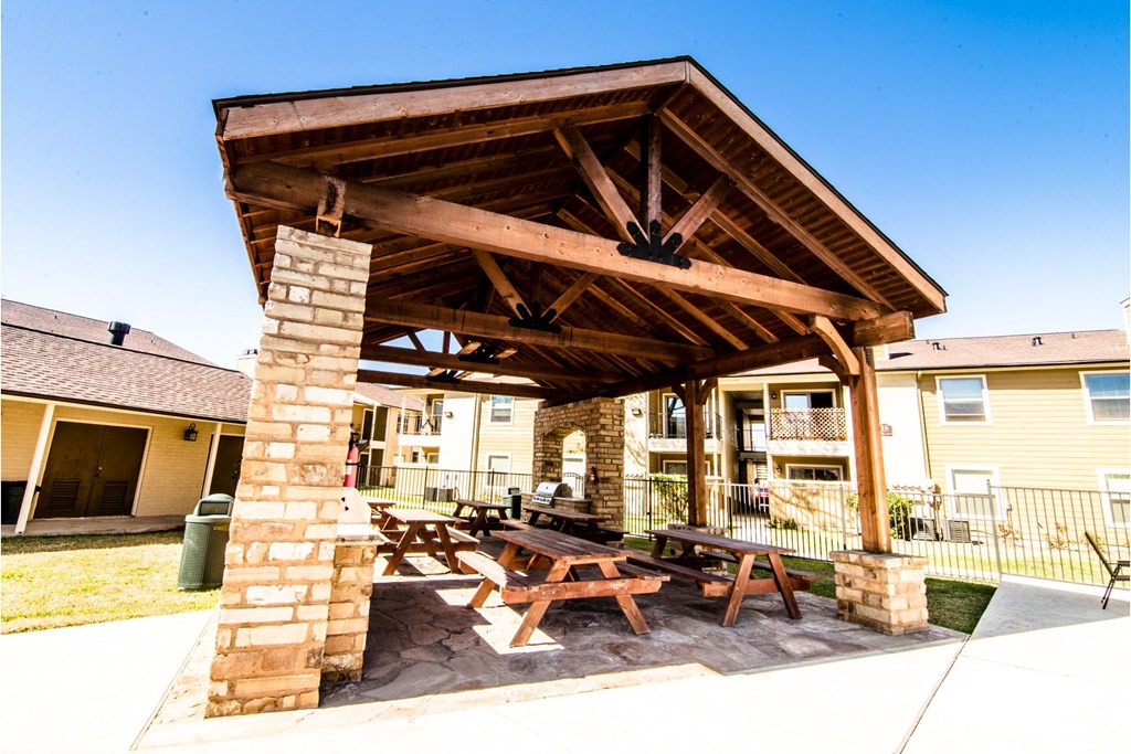 a picnic area with a stone column and a wooden roof