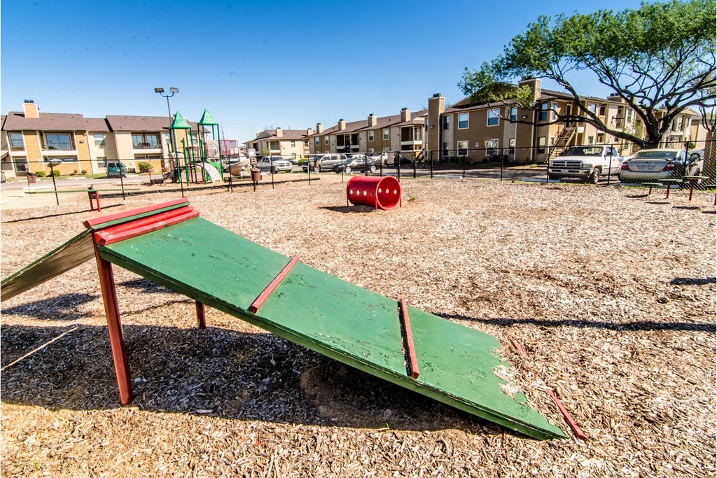 a green and red park bench in a park with houses in the background
