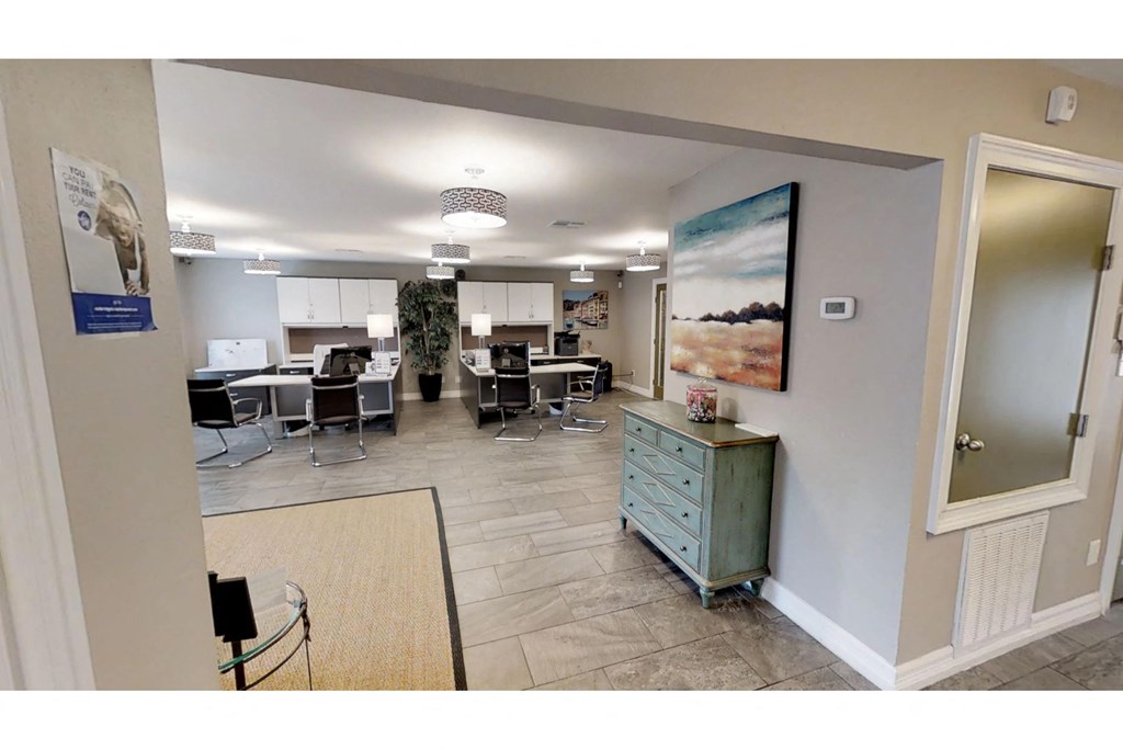 a room with a desk and chairs and a large painting on the wall