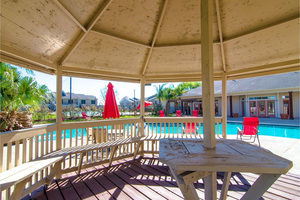 a large deck with a picnic table and a pool in the background