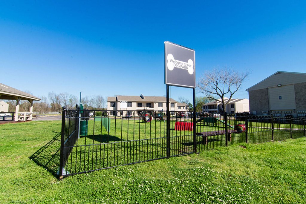 a sign in front of a park with houses in the background