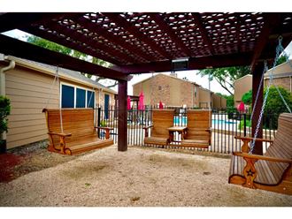 a patio with a swing and a pool in the background
