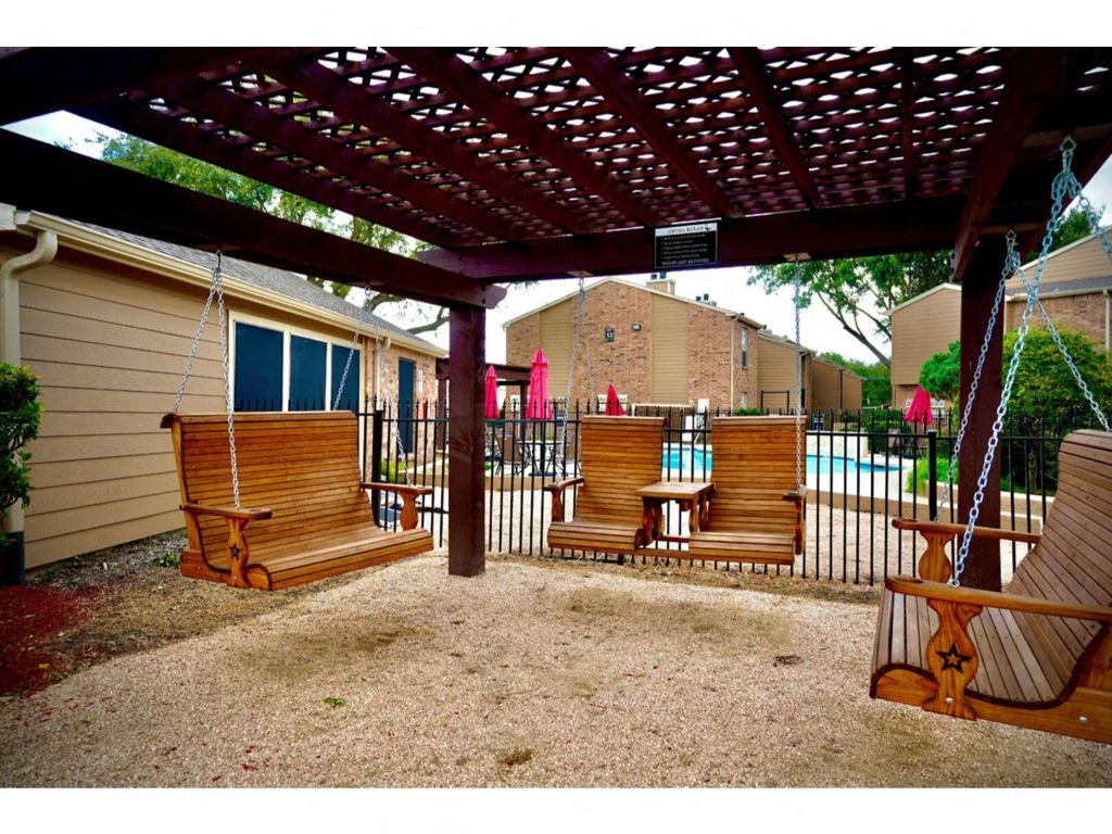 a patio with a swing and a pool in the background