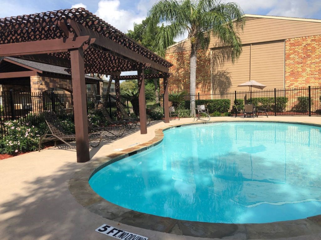 a pool with a pergola and a building in the background