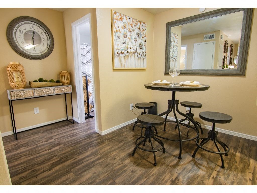 a room with a table and three stools in front of a large mirror