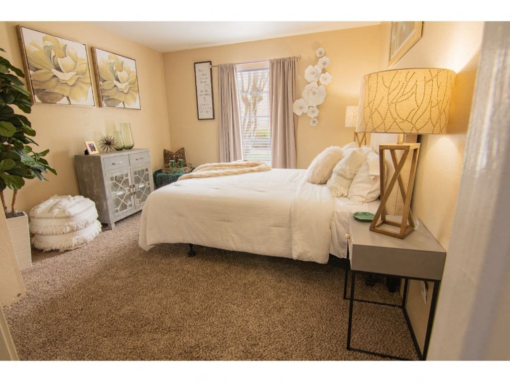 a bedroom with a bed and a dresser with a lamp on it