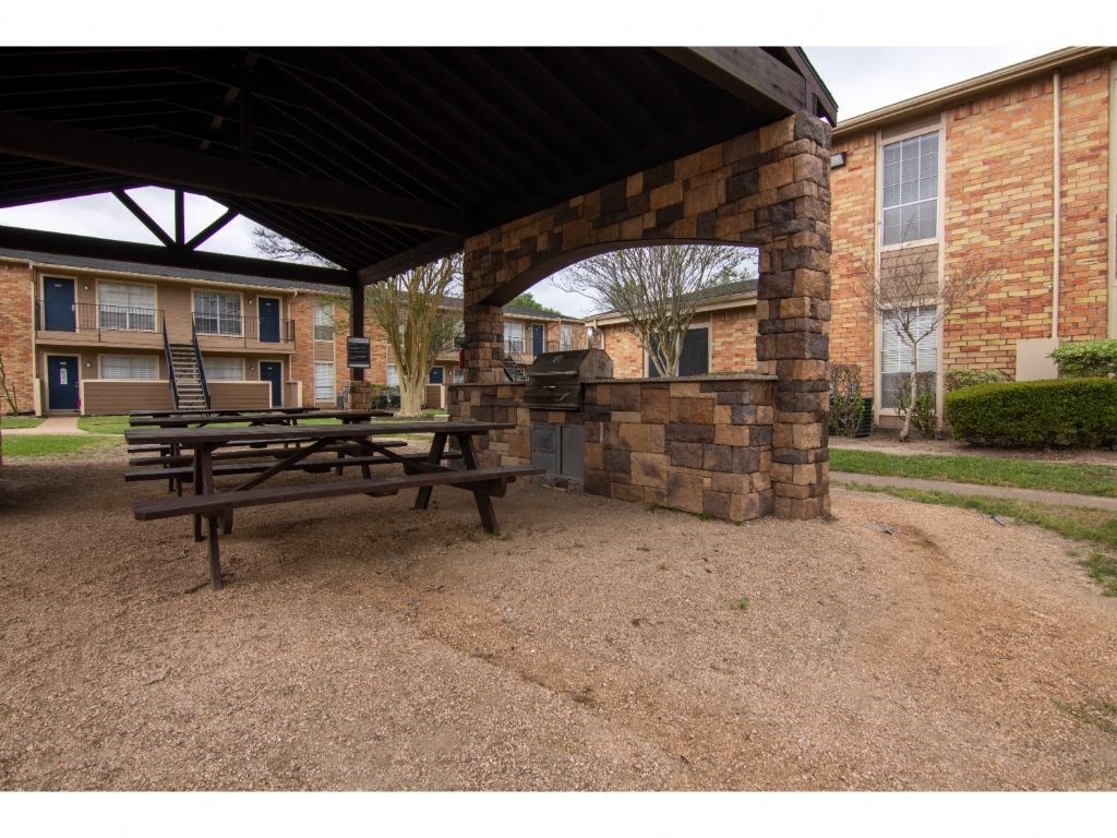 a picnic table with a grill in front of a brick building