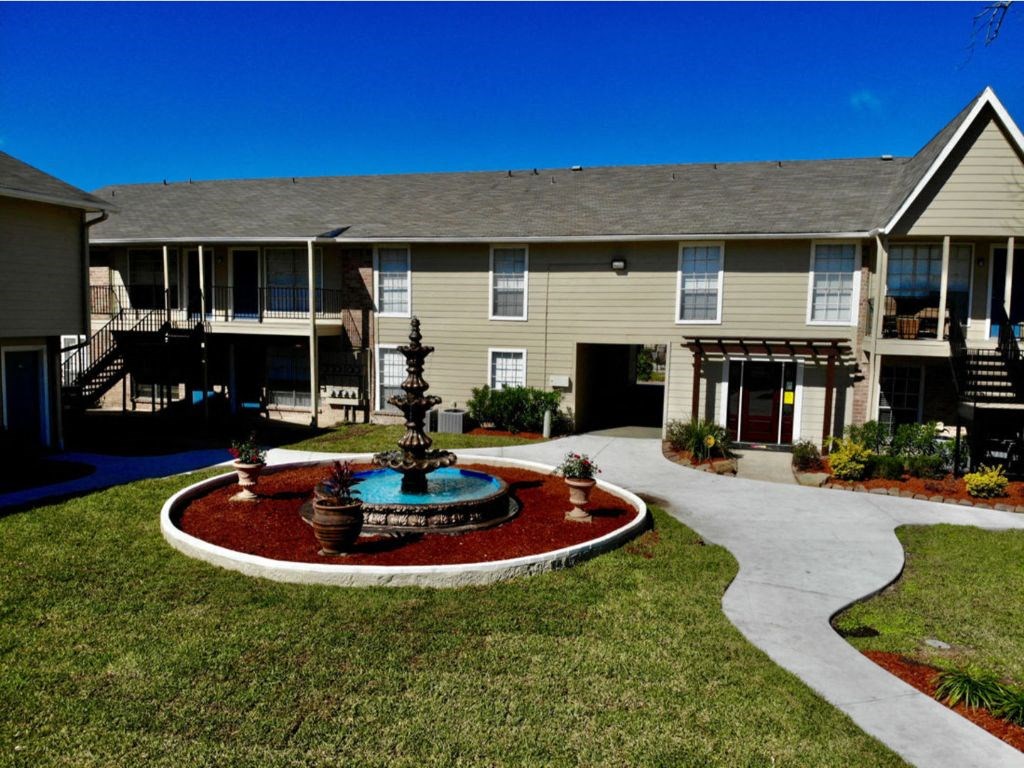 a fountain in the middle of a yard in front of a building