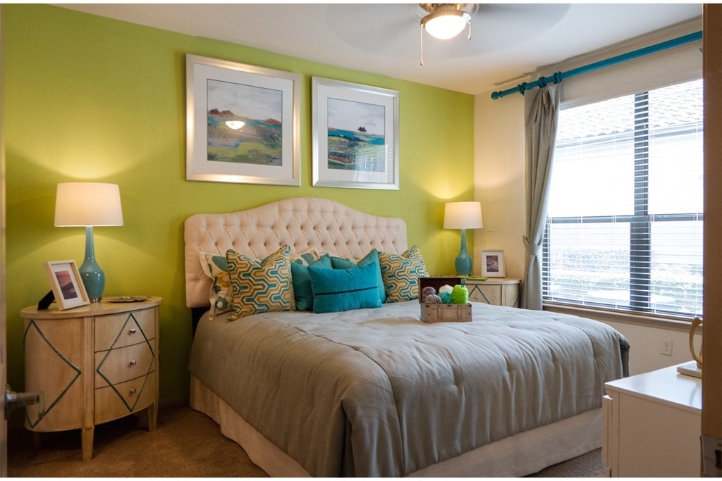 a bedroom with green walls and a bed with a white tufted headboard