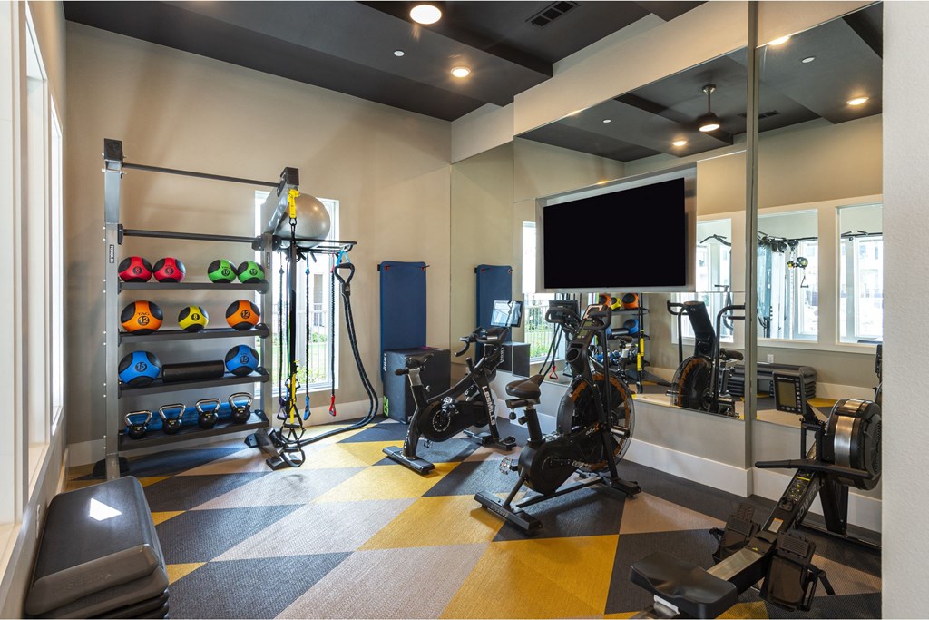 a spacious fitness room with cardio equipment and a flat screen tv