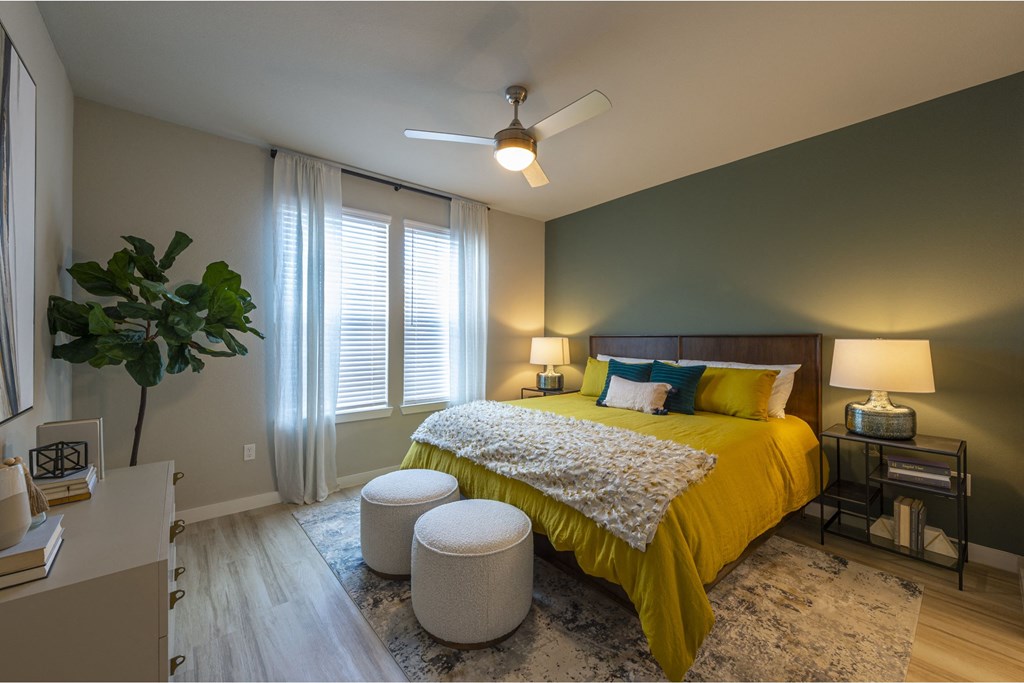 a bedroom with a large yellow bed and two white stools at the foot of the bed
