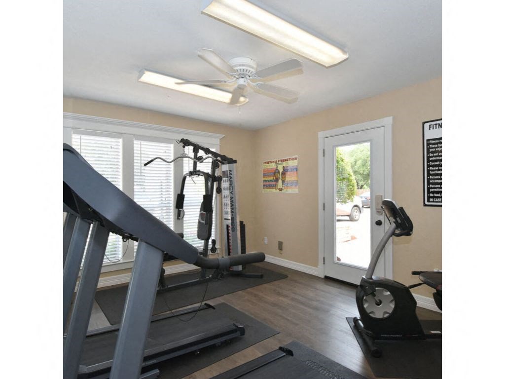a home gym with a treadmill and a ceiling fan