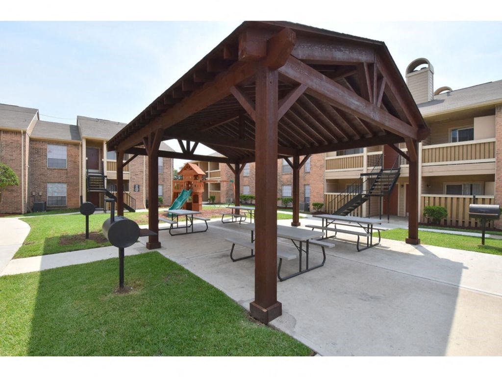 a gazebo with benches in front of a brick building