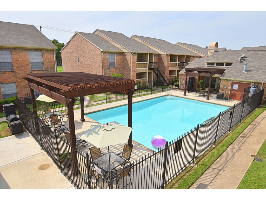 a swimming pool with a gazebo and tables and chairs in front of a brick