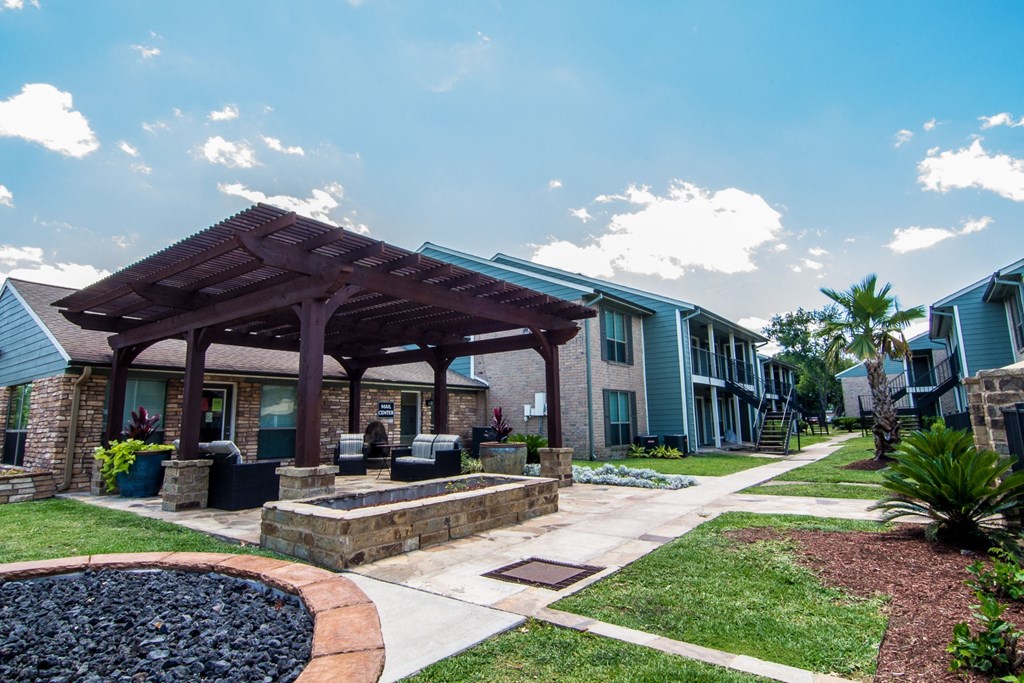a patio with a firepit and a pergola at the whispering winds apartments in pear