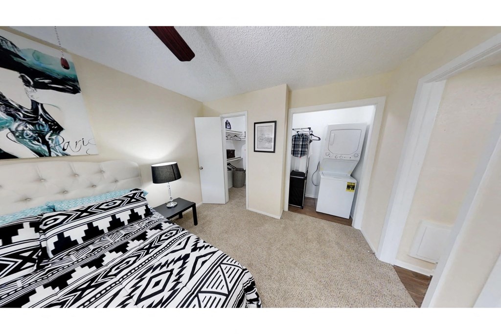 a bedroom with a bed and a closet with a washer and dryer