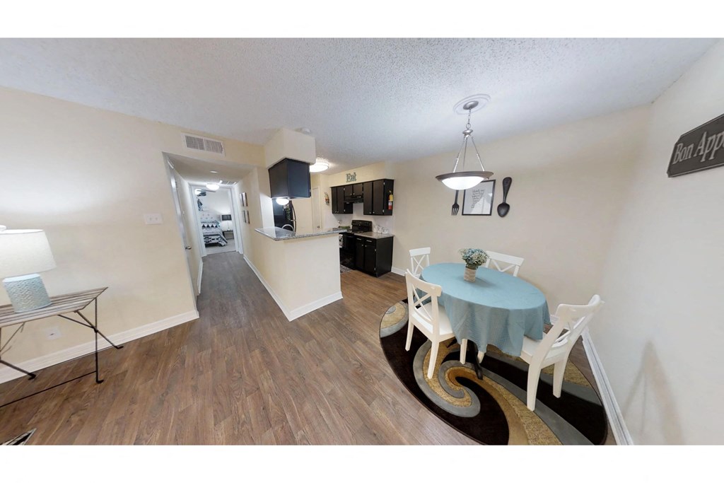 a dining area with a table and chairs and a kitchen in the background