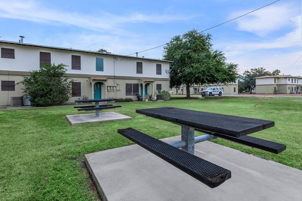 a picnic area with two picnic tables and a building in the background
