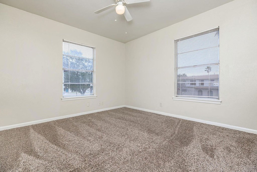 a bedroom with two windows and a ceiling fan