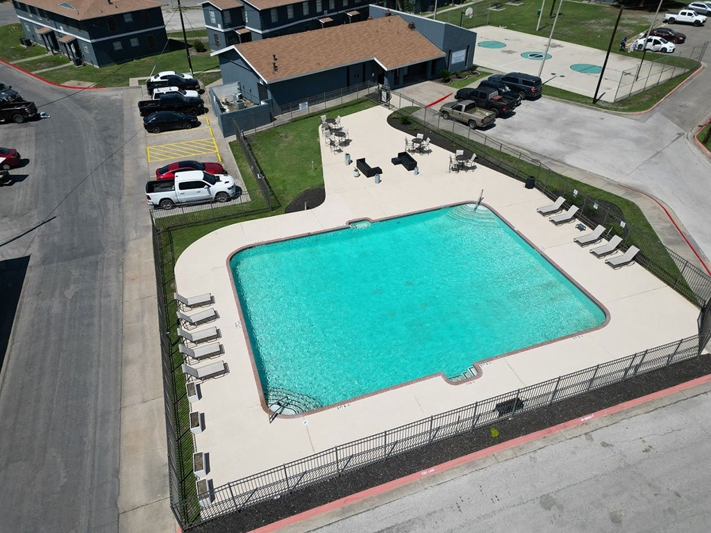 an aerial view of a large swimming pool with a building in the background