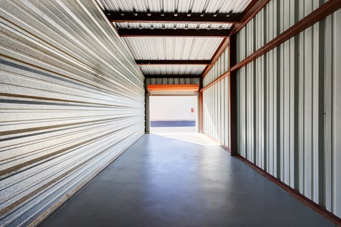 A long, narrow corridor with a metallic wall on one side and a wooden wall on the other.