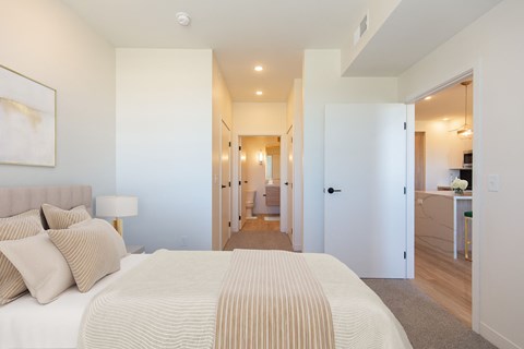a bedroom with a large bed and a hallway to a bathroom