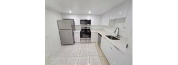 A kitchen with white cabinets and a stainless steel refrigerator.