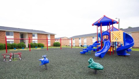 A playground with a blue slide and a red and blue playhouse.