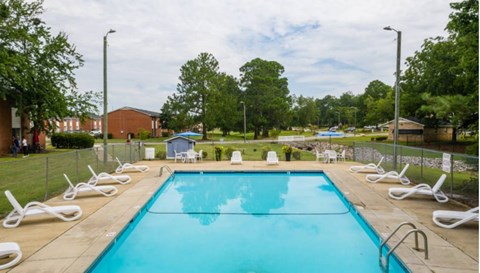 A large swimming pool surrounded by white lounge chairs.