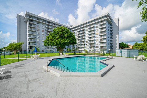 A large apartment complex with a pool in the foreground.