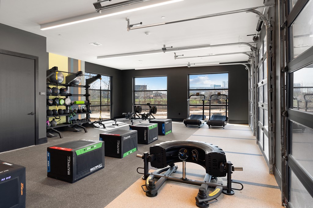 a workout room with weights and other equipment in a room with windows