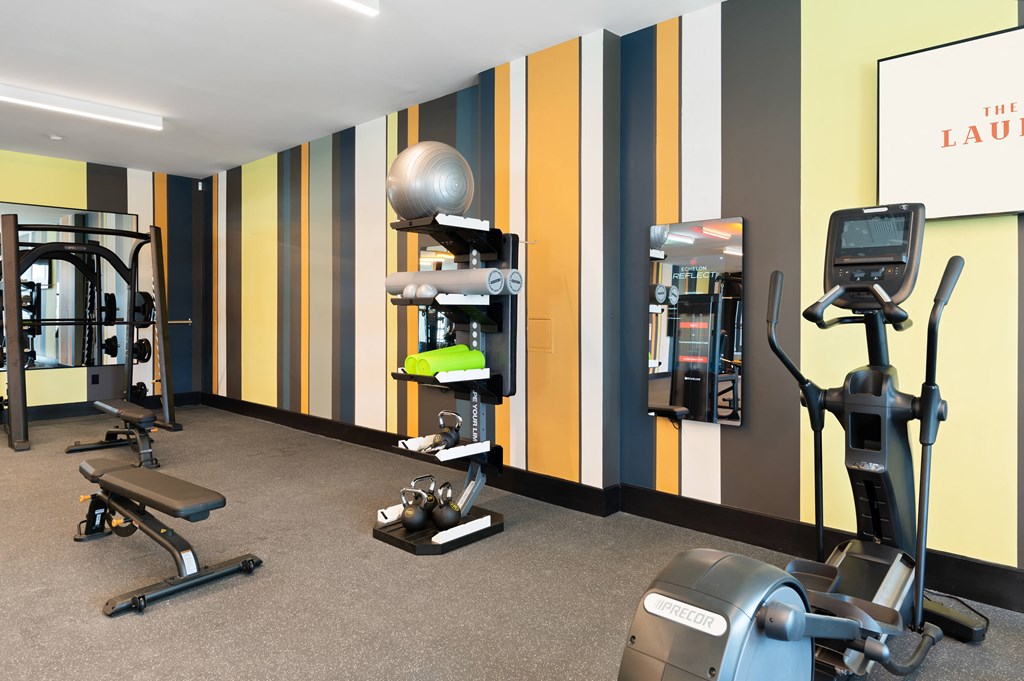 a gym with exercise equipment and weights in a room with striped walls