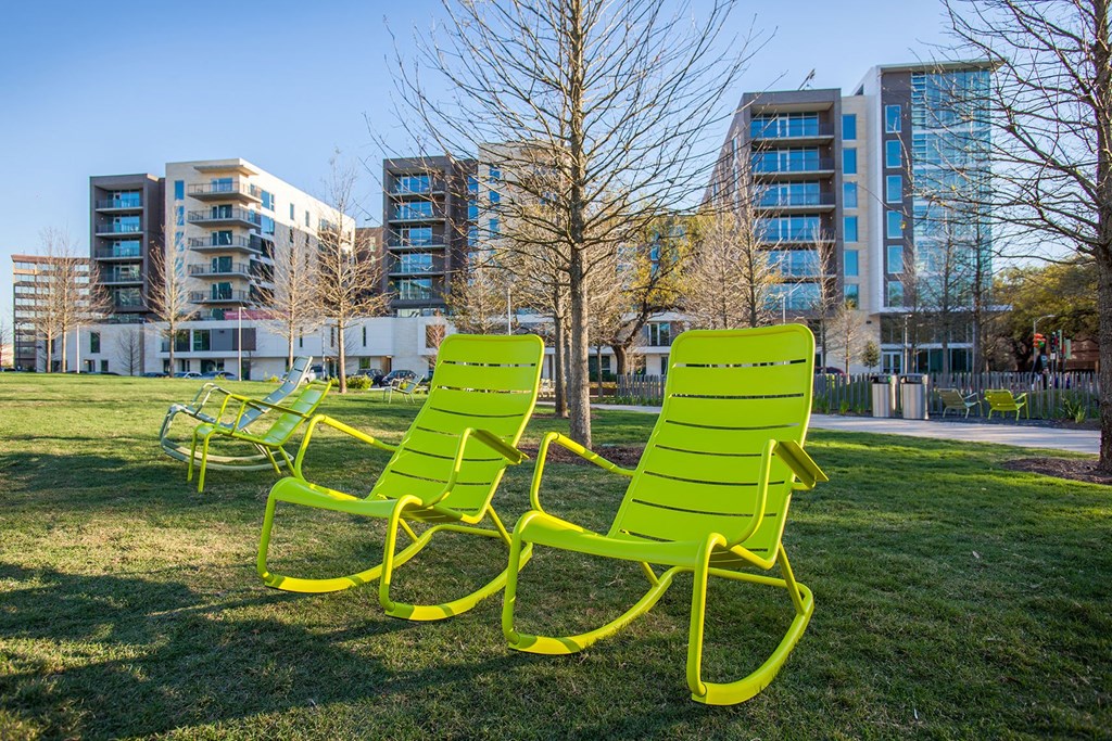 a group of green lawn chairs sitting in a park
