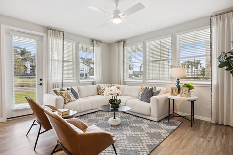 A living room with a white couch, a brown chair, and a ceiling fan.