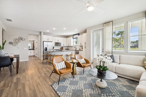 A modern living room with a dining area and kitchen in the background.