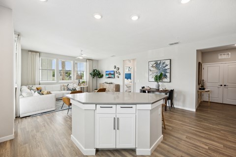 A modern kitchen with white cabinets and a wooden floor.