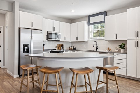 A kitchen with white cabinets and a bar area with stools.