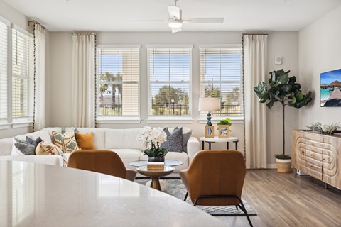 A living room with a white couch, a coffee table, and a ceiling fan.